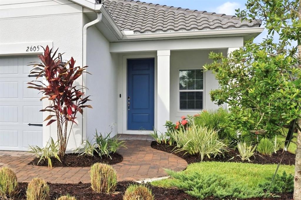 A blue front door stands at the entrance of a house with a paved walkway — 2605 STAR APPLE WAY, SARASOTA, FL