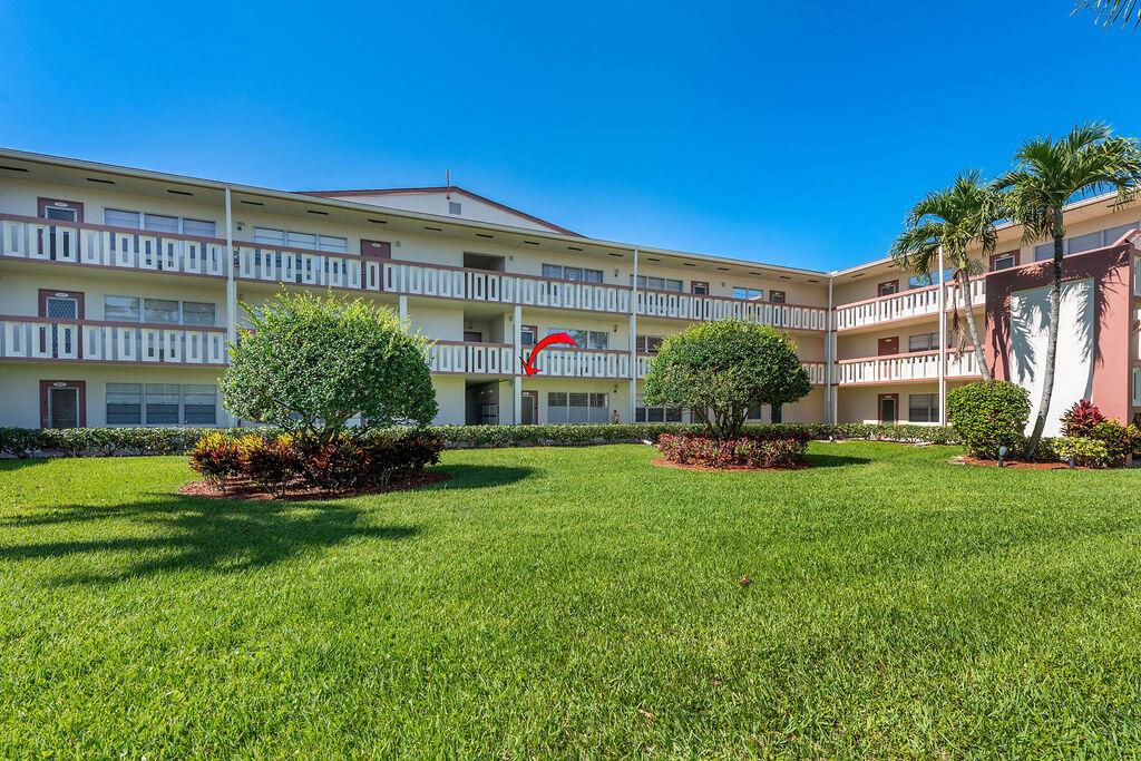 A three-story apartment building with a lawn and palm trees under a clear sky — 301 Preston H # 301, Boca Raton FL 33434, BOCA RATON, FL