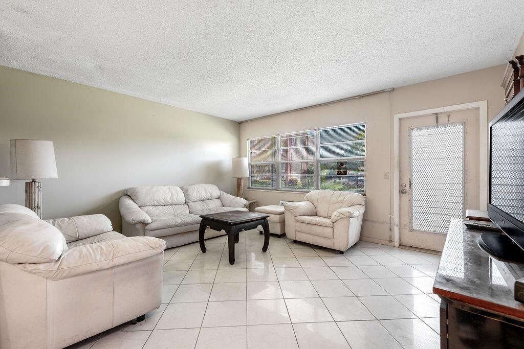 A living room with white tile floors, a white sofa set, and a glass door — 301 Preston H # 301, Boca Raton FL 33434, BOCA RATON, FL