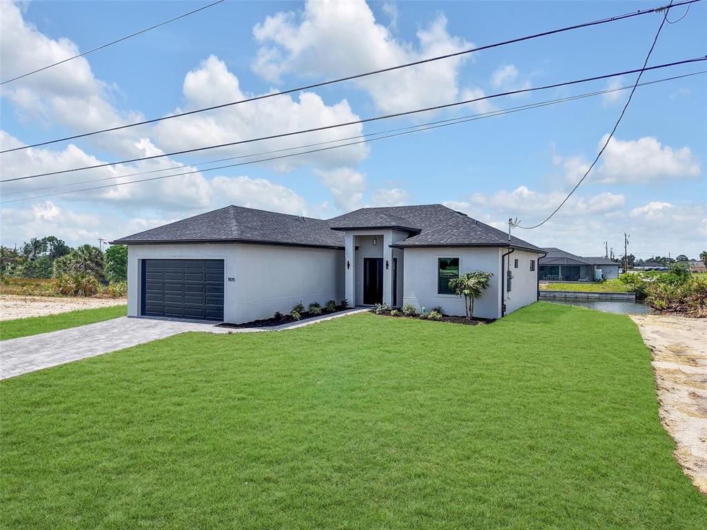 A modern single-story house with a gray exterior, dark roof, and attached two-car garage — 1505 NW 17TH STREET, CAPE CORAL, FL