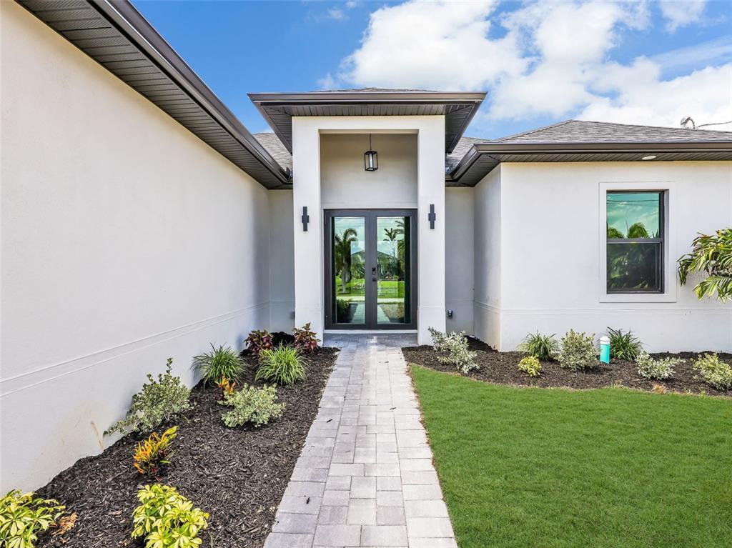A paved walkway leads to the front entrance of a modern home with white stucco — 1505 NW 17TH STREET, CAPE CORAL, FL
