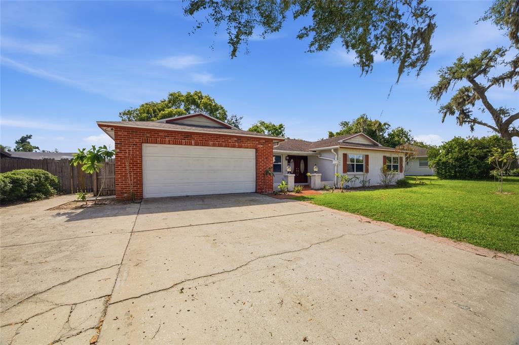 A single-story house with a brick garage, white siding, and a cracked concrete driveway — 2969 FOREST CIRCLE, SEFFNER, FL