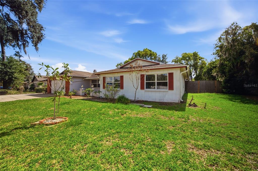 A single-story house with white siding, red shutters, and a front lawn under a blue sky — 2969 FOREST CIRCLE, SEFFNER, FL
