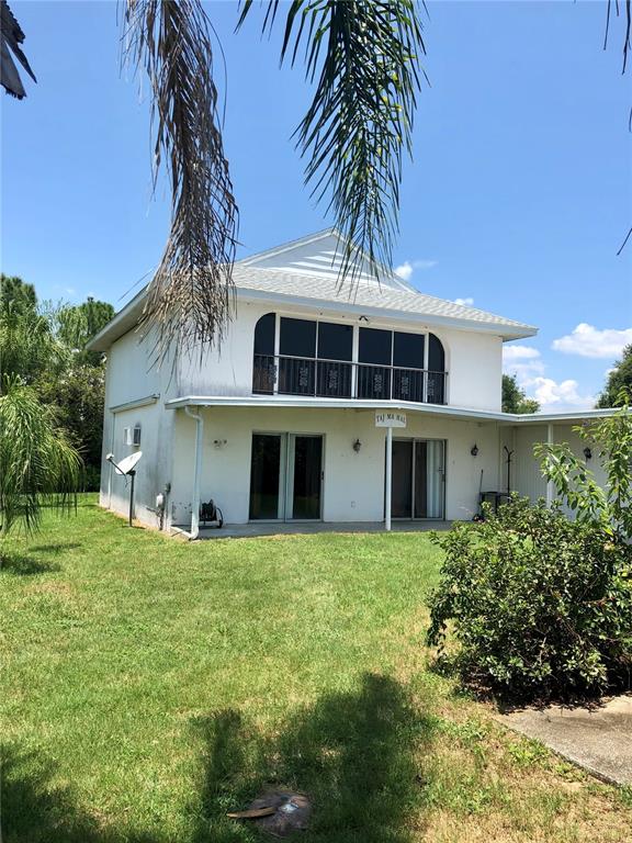 A two-story white house with a screened-in balcony and a grassy backyard — 1003 DORA AVENUE, TAVARES, FL