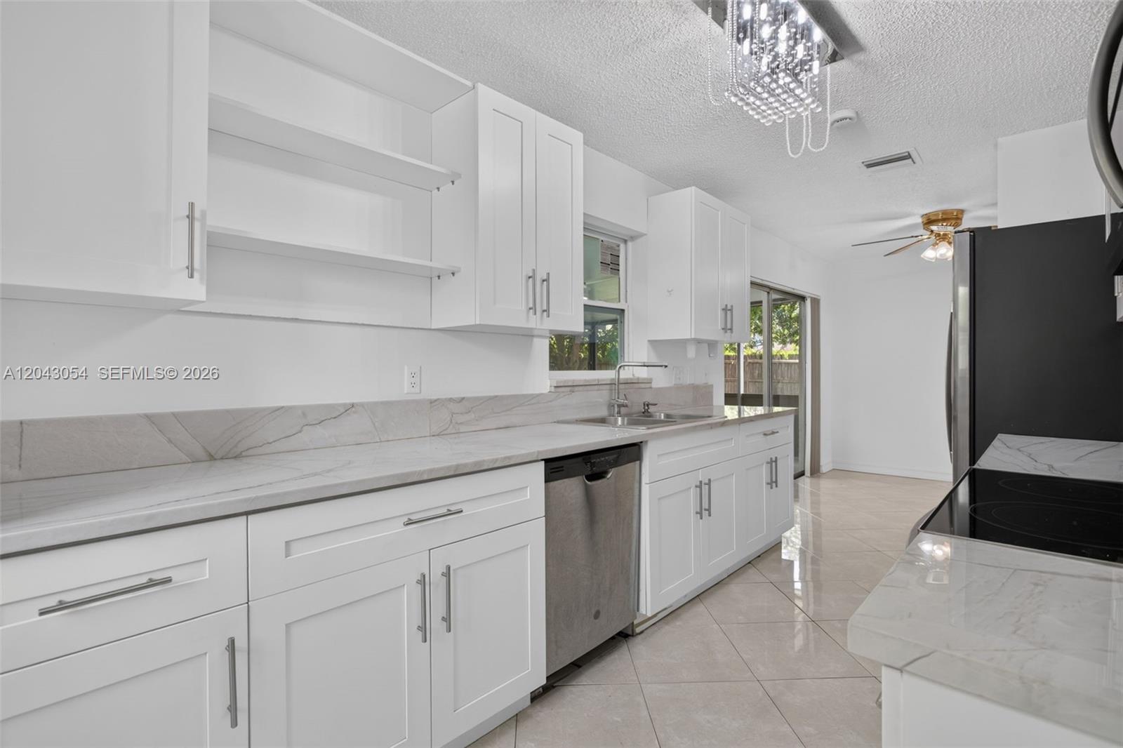 A modern kitchen features white cabinets, marble-style countertops, stainless steel appliances, and tile flooring — 2640 NW 67th Ter, Margate FL 33063, MARGATE, FL