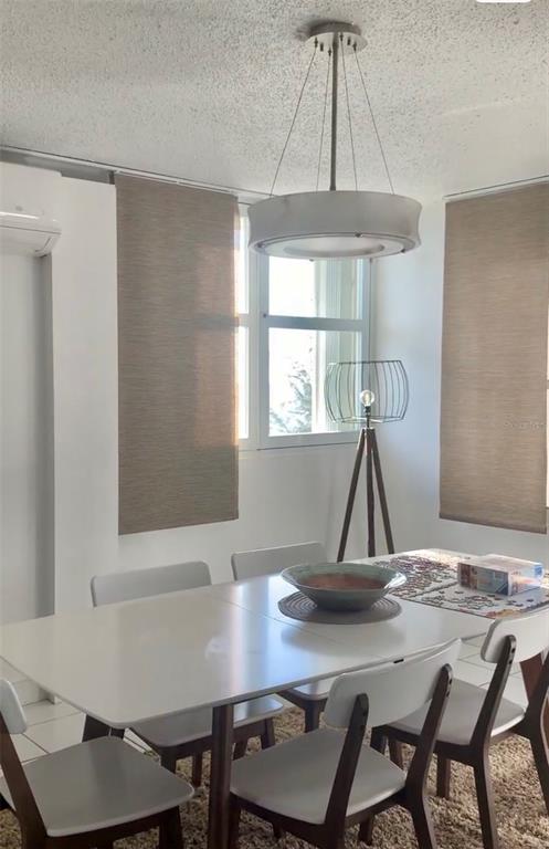 A bright living and dining area features white tile floors, ocean views, and a balcony — 4939 ISLA VERDE AVE. UNIT 601, CAROLINA, PR