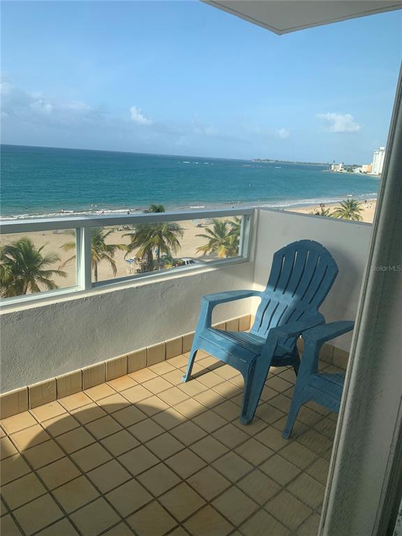 A dining room with a white table, six chairs, and large windows overlooking the ocean — 4939 ISLA VERDE AVE. UNIT 601, CAROLINA, PR