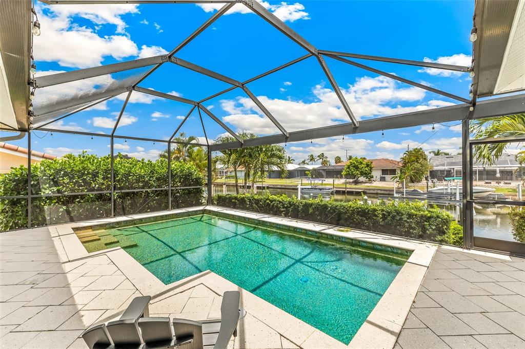 A screened-in pool patio overlooks a canal with boats and neighboring houses — 2477 SIERRA LANE, PUNTA GORDA, FL
