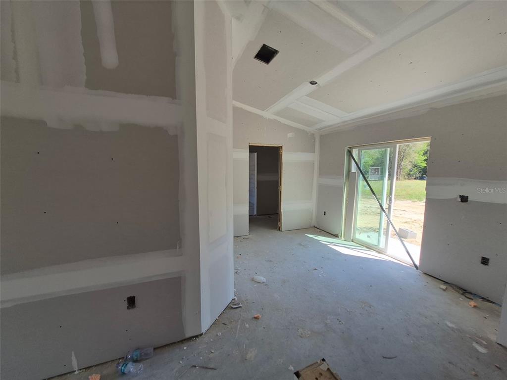 An unfinished room features drywall, a vaulted ceiling, and a sliding glass door — 7640 SW 14 STREET, OCALA, FL