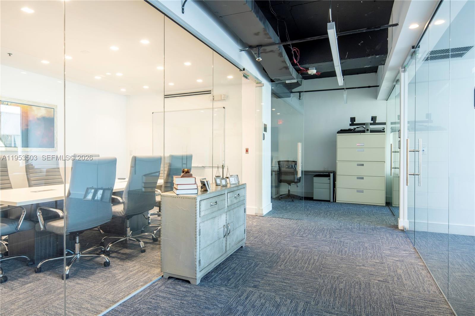 A modern office suite features glass-walled conference rooms, a metal cabinet, and carpeted flooring — 150 SE 2nd Ave # 1410, Miami FL 33131, MIAMI, FL