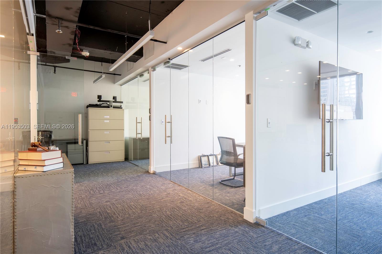 An office interior features glass-walled rooms, blue carpet, and an exposed black ceiling — 150 SE 2nd Ave # 1410, Miami FL 33131, MIAMI, FL