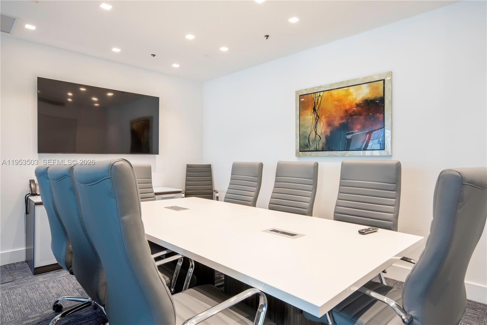 A modern conference room features a white table, gray chairs, and wall-mounted television — 150 SE 2nd Ave # 1410, Miami FL 33131, MIAMI, FL