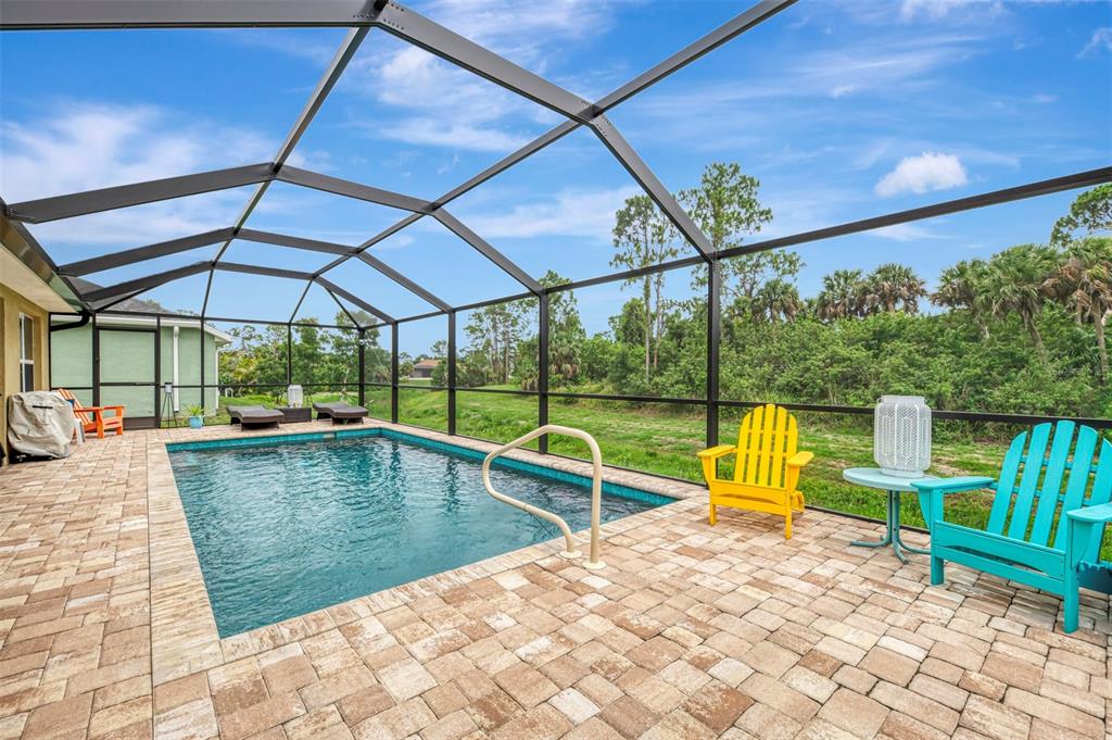 A swimming pool with a screen enclosure and patio furniture sits in a backyard — 2443 LANCASTER LANE, NORTH PORT, FL