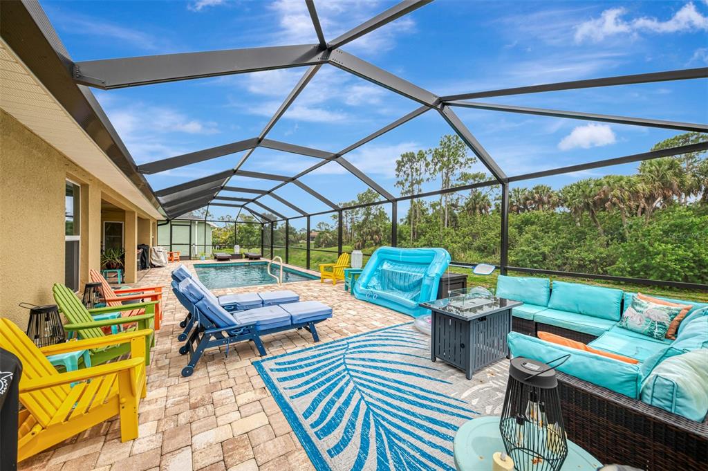 A screened-in patio features a swimming pool, outdoor furniture, and a patterned area rug — 2443 LANCASTER LANE, NORTH PORT, FL