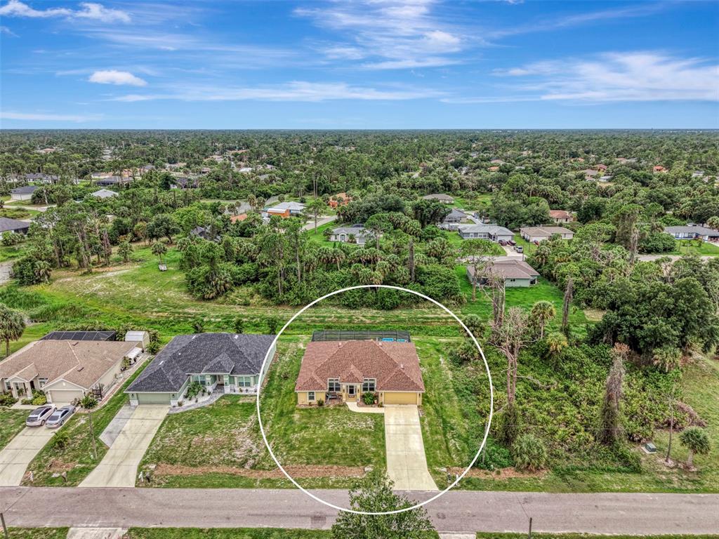 An aerial view shows a single-story house with a pool enclosure in a suburban neighborhood — 2443 LANCASTER LANE, NORTH PORT, FL