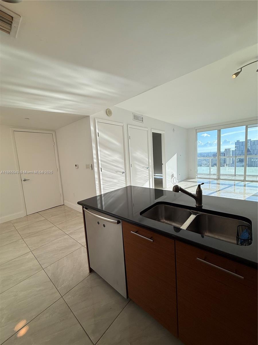 A kitchen island with a stainless steel dishwasher and sink faces a bright living area — 50 Biscayne Blvd # 3405, Miami FL 33132, MIAMI, FL