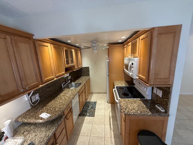 A galley kitchen features light wood cabinets, granite countertops, and stainless steel appliances — 3092 Westbury H # 3092, Deerfield Beach FL 33442, DEERFIELD BEACH, FL