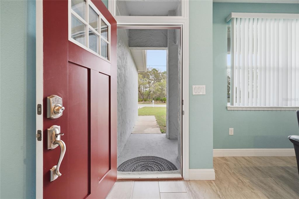 An open red front door reveals a covered entryway and a view of a grassy yard — 2118 W HAMPSHIRE BOULEVARD, CITRUS SPRINGS, FL