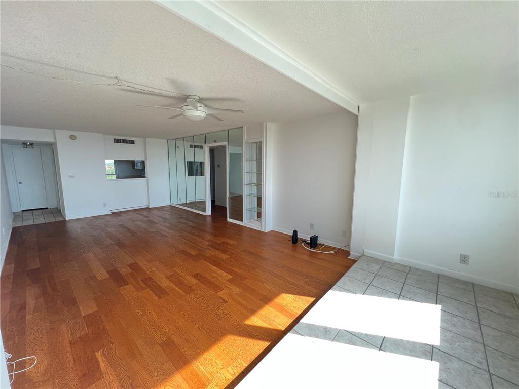 An open-concept living area features hardwood flooring, a ceiling fan, and mirrored wall panels — 2616 COVE CAY DRIVE UNIT 701, CLEARWATER, FL