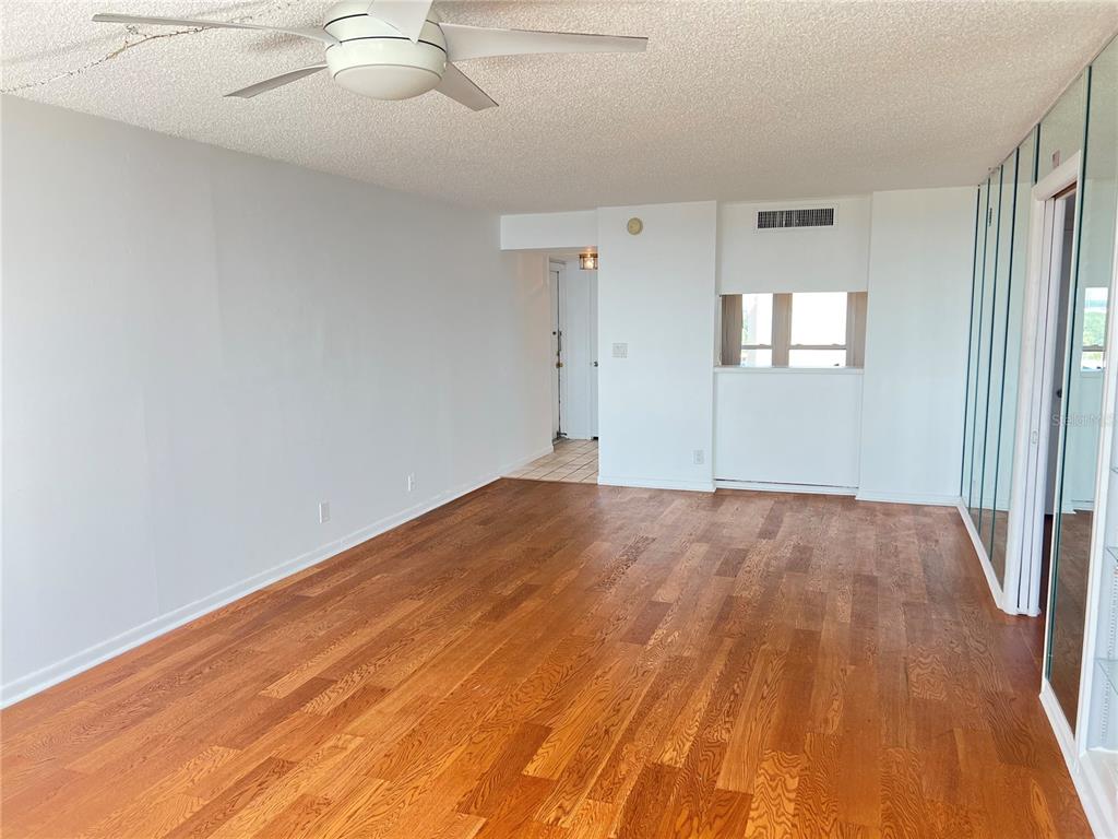 An empty room with hardwood floors, a ceiling fan, and mirrored closet doors — 2616 COVE CAY DRIVE UNIT 701, CLEARWATER, FL