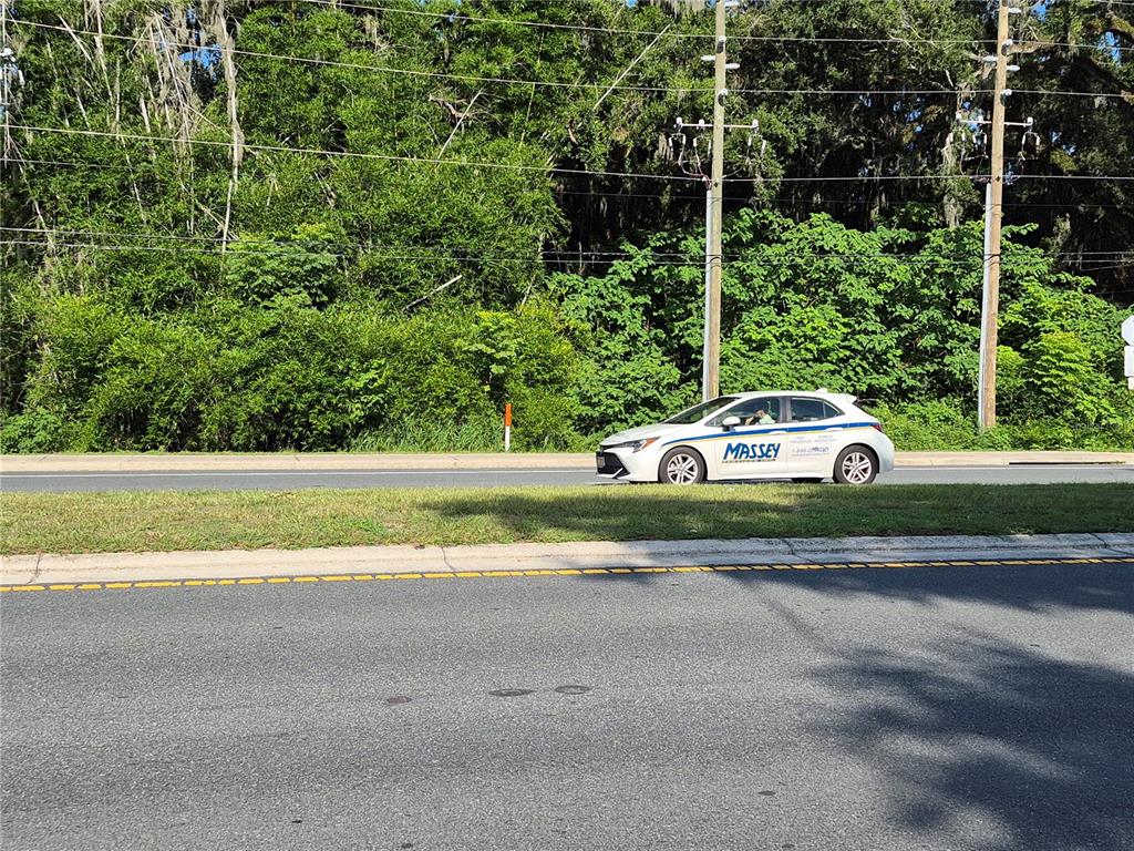 A white Massey Services car drives along a road in front of a wooded area — 12267 N US HIGHWAY 301, OXFORD, FL