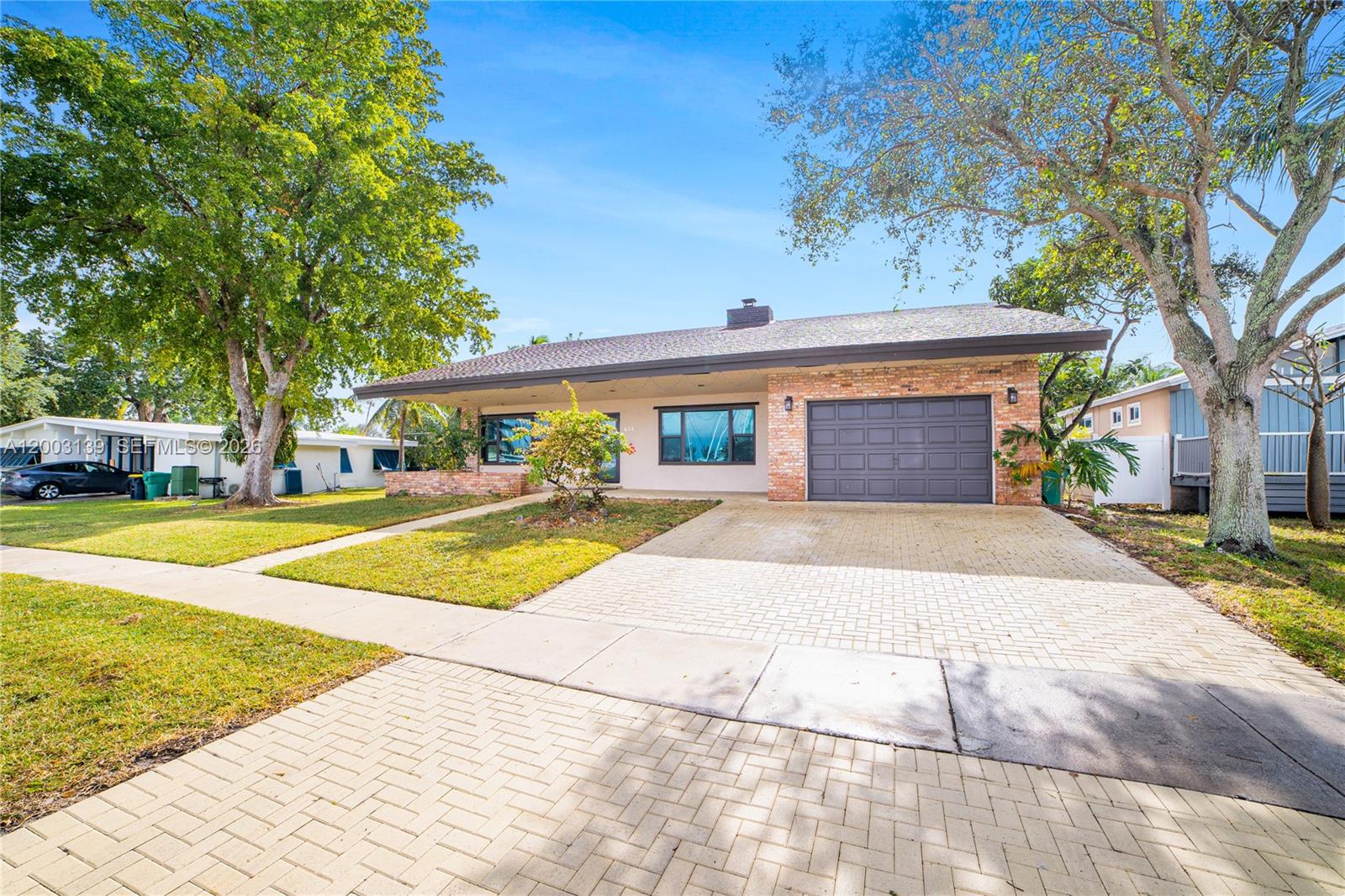 A single-story house with a brick facade, dark garage door, and a paved driveway — 614 NE 3rd St, Dania Beach FL 33004, DANIA BEACH, FL