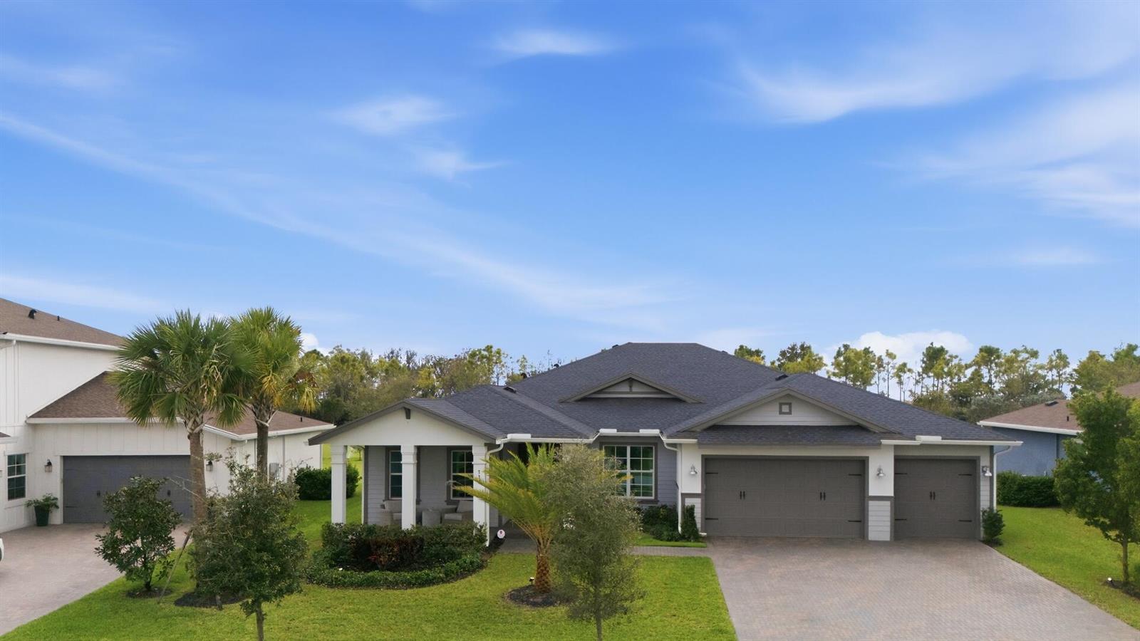 A single-story house with a gray shingled roof, a three-car garage, and a front porch — 732 Hookline Circle, Loxahatchee FL 33470, LOXAHATCHEE, FL
