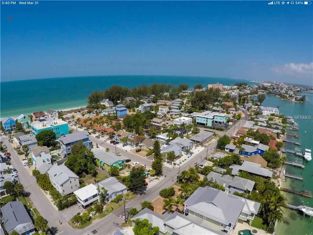 A two-story lime green building features a bright pink door and a blue awning — 61 81ST AVENUE UNIT 3, TREASURE ISLAND, FL