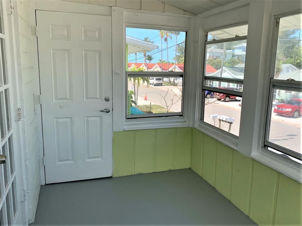 A covered porch features white French doors, a white six-panel door, and a window — 61 81ST AVENUE UNIT 3, TREASURE ISLAND, FL