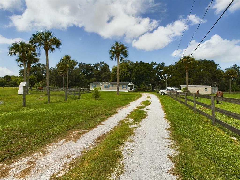 A gravel driveway leads to a mobile home on a grassy lot with palm trees — 945 NE 28th Avenue, Okeechobee FL 34972, OKEECHOBEE, FL