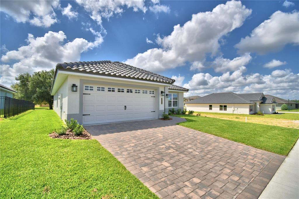 A single-story house with a white garage, tiled roof, and a paved driveway — 4514 GRANDVIEW GLEN DRIVE, AUBURNDALE, FL