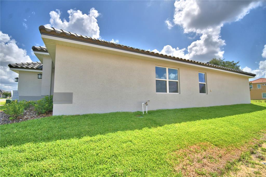 The side exterior of a beige stucco house features a tiled roof and two windows — 4514 GRANDVIEW GLEN DRIVE, AUBURNDALE, FL