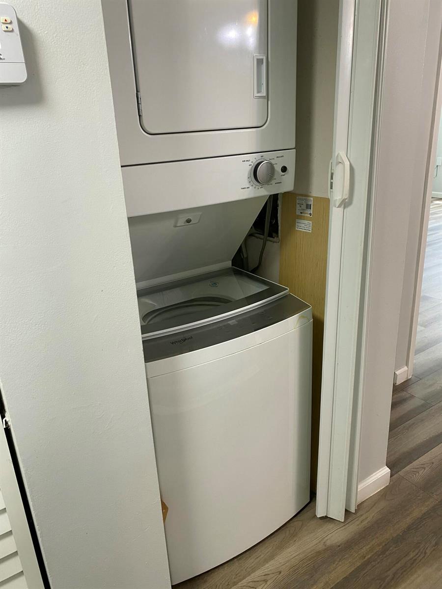 A white stacked Whirlpool washer and dryer unit sits inside a small laundry closet — 6890 Royal Palm Boulevard # 209h, Margate FL 33063, MARGATE, FL