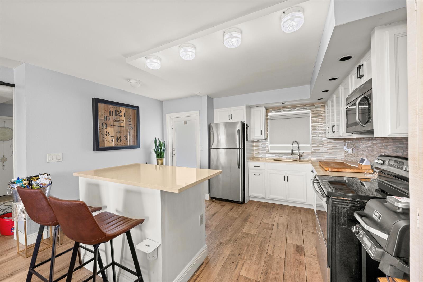 A kitchen features white cabinets, stainless steel appliances, a center island, and wood-look flooring — 231 E Lantana Road # 402, Lantana FL 33462, LANTANA, FL