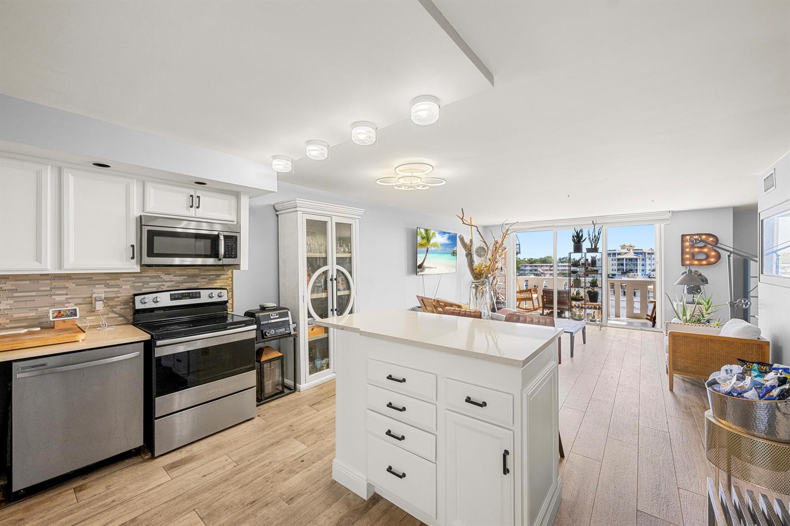 A kitchen with white cabinets and a center island opens to a living area — 231 E Lantana Road # 402, Lantana FL 33462, LANTANA, FL