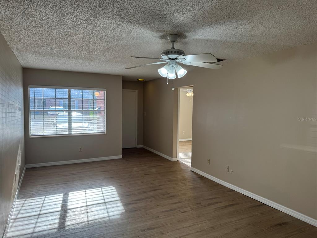 An empty living room features wood-look flooring, a ceiling fan, and a window with blinds — 1241 HERITAGE LANE, ORLANDO, FL