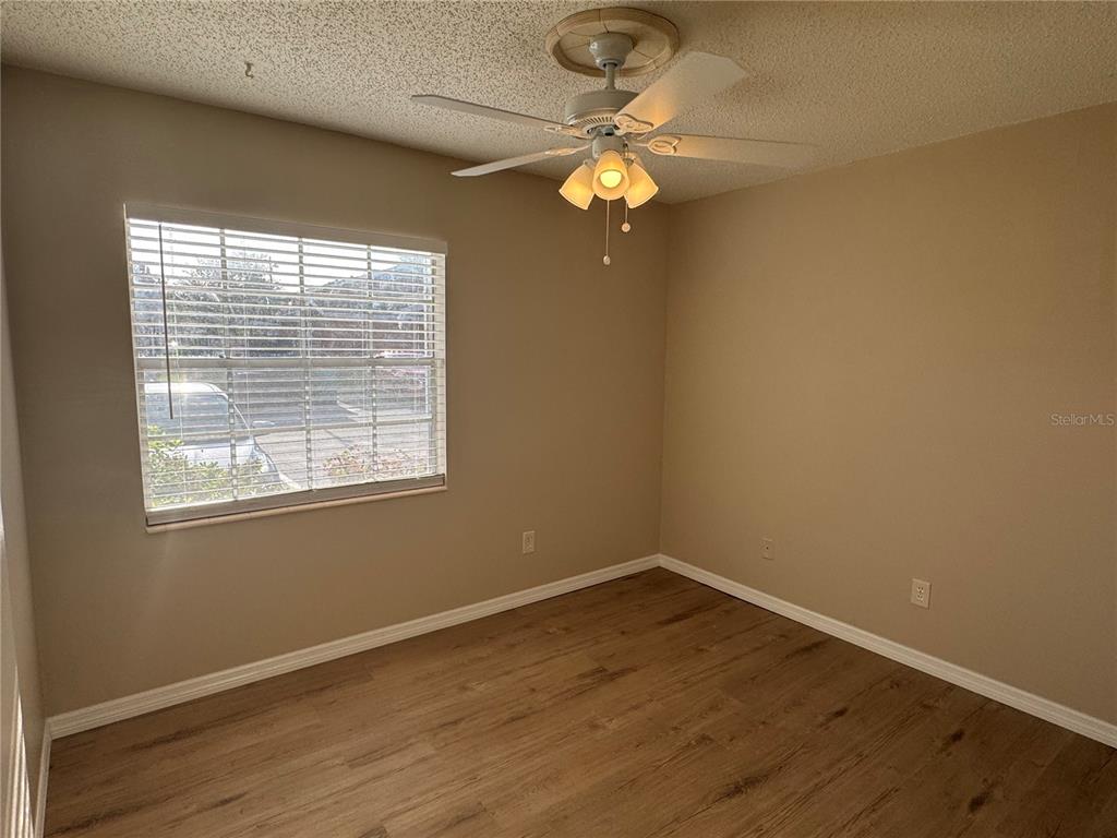 An empty bedroom features light brown walls, wood-look flooring, a ceiling fan, and a window — 1241 HERITAGE LANE, ORLANDO, FL