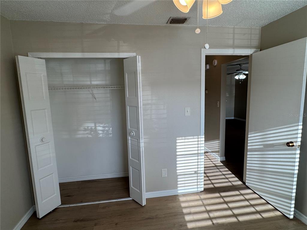 A bedroom features light-colored walls, wood-look flooring, a closet with double doors, and an entryway — 1241 HERITAGE LANE, ORLANDO, FL