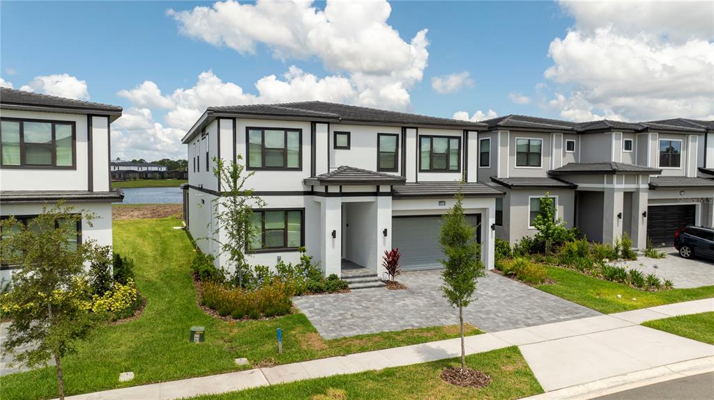 A two-story modern house with a gray garage, white stucco exterior, and a paved driveway — 10018 VOYAGER WAY, ORLANDO, FL