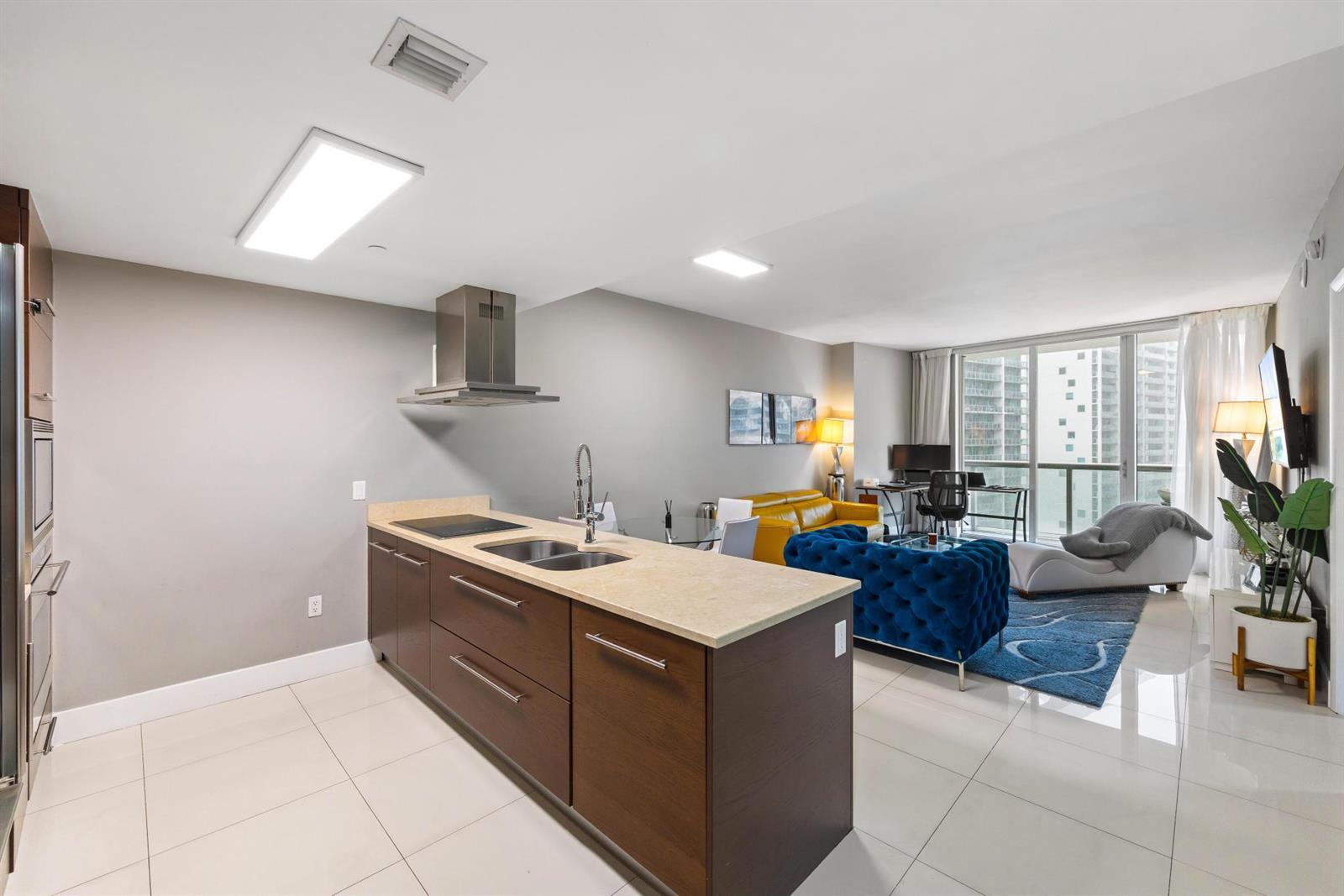 A modern open-concept kitchen and living area with dark wood cabinetry and tile flooring — 485 Brickell Avenue # 2506, Miami FL 33131, MIAMI, FL
