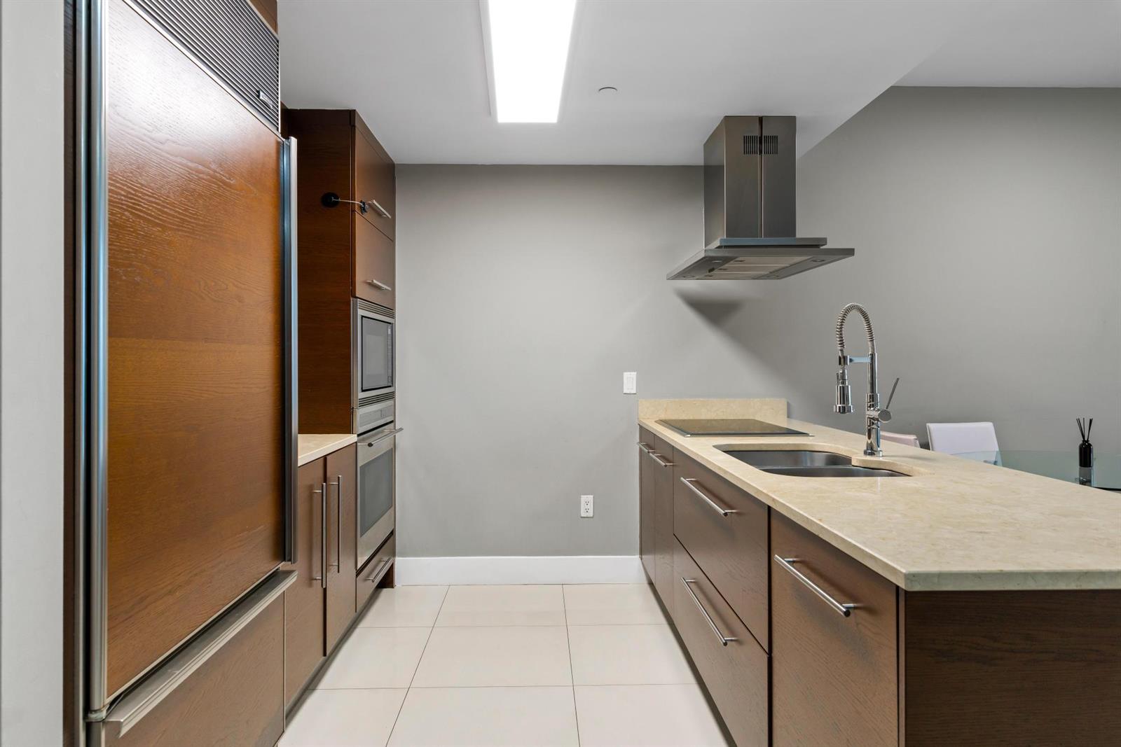 A modern kitchen features wood cabinets, a stone countertop, stainless steel appliances, and tile flooring — 485 Brickell Avenue # 2506, Miami FL 33131, MIAMI, FL