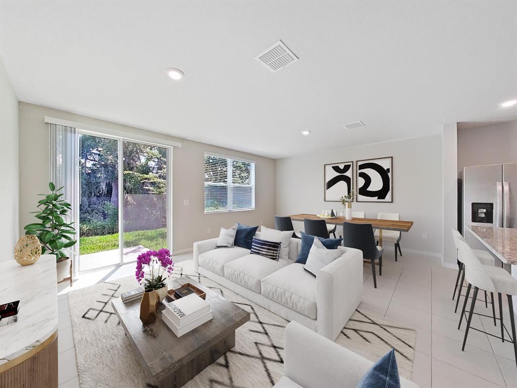 A bright, open-concept living and dining area features a white sofa, wooden table, and patio — 2763 SCARLET BAY PLACE, BRANDON, FL