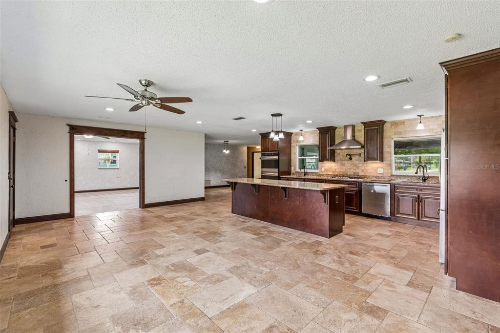 A kitchen with a large island, dark wood cabinets, and stone tile flooring — 1322 W VOORHIS AVENUE, DELAND, FL
