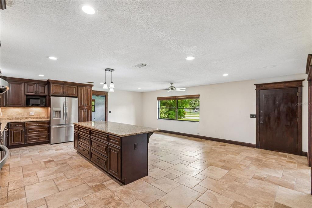 A kitchen with dark wood cabinets, granite countertops, a large island, and tiled flooring — 1322 W VOORHIS AVENUE, DELAND, FL