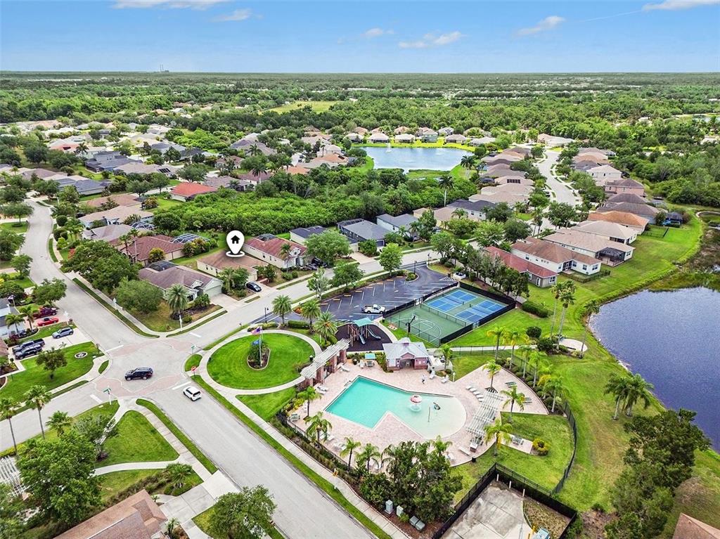 An aerial view shows a suburban neighborhood with a community pool, tennis courts, and houses — 11567 57TH STREET CIRCLE E, PARRISH, FL