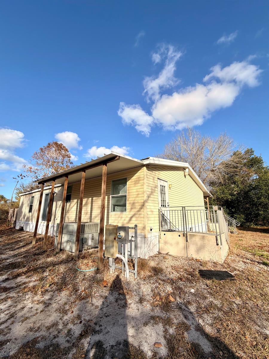 A single-story manufactured home with yellow siding, a covered porch, and a metal railing — 1907 NE 308th Street, Okeechobee FL 34972, OKEECHOBEE, FL
