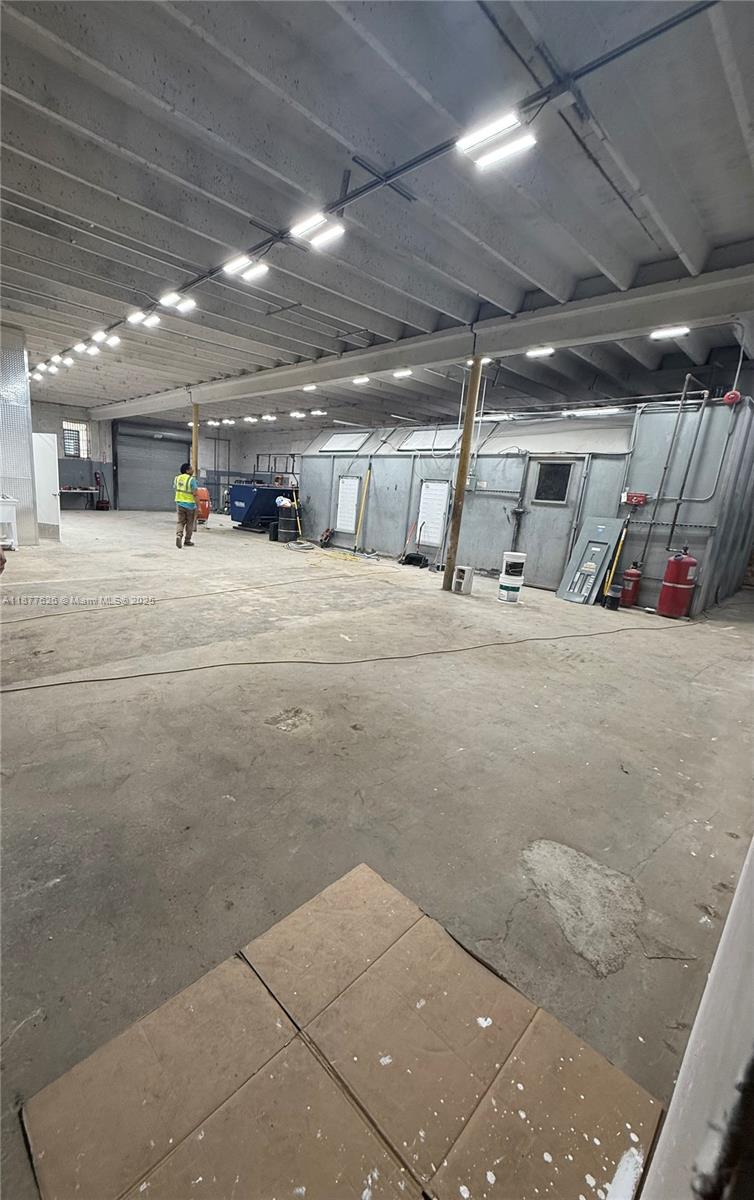 A large industrial warehouse space features a concrete floor, exposed ceiling beams, and a spray booth — 572 NW 72nd St, Miami FL 33150, MIAMI, FL