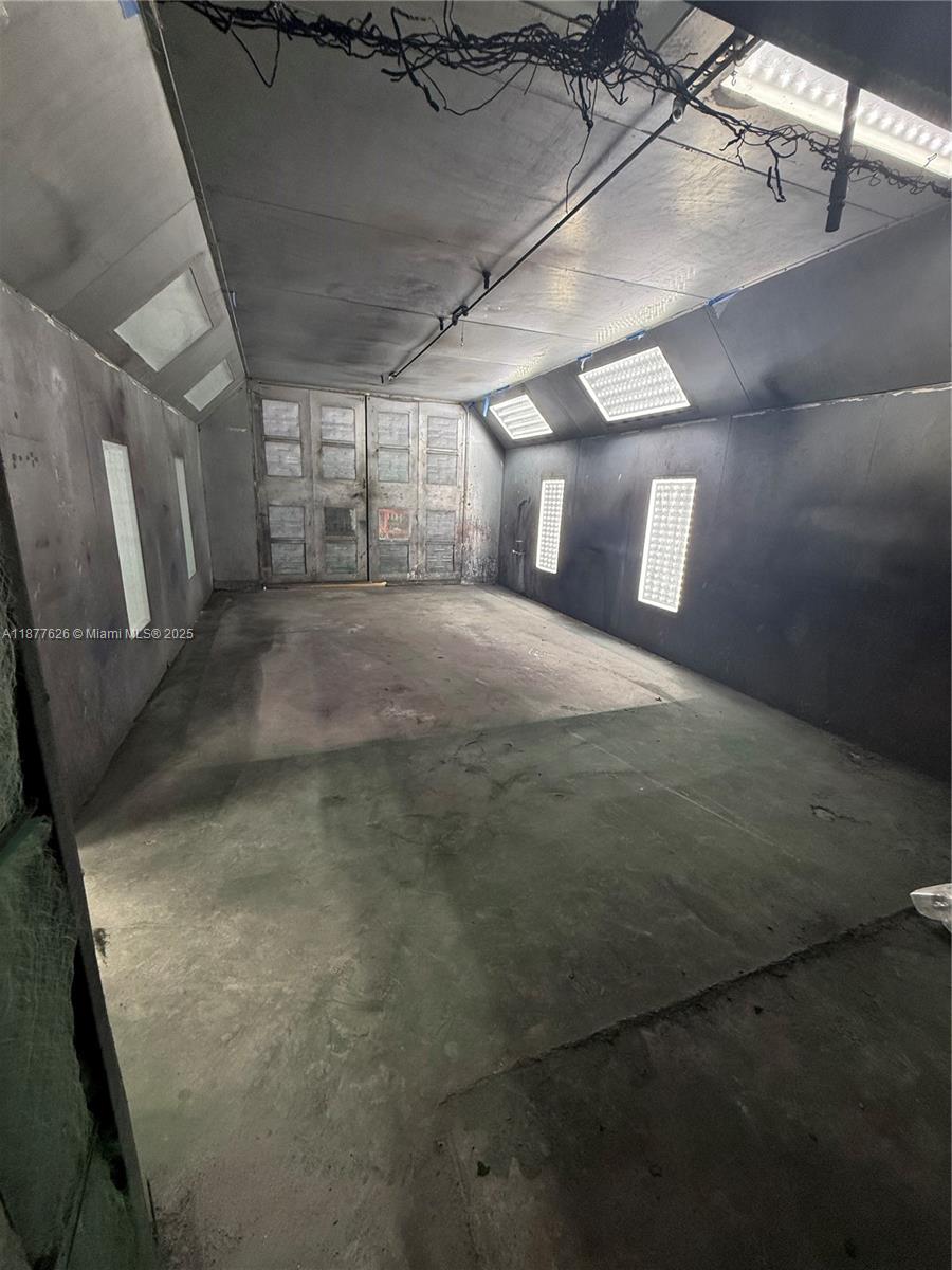 This is an industrial paint spray booth with metal walls, concrete floors, and overhead lighting — 572 NW 72nd St, Miami FL 33150, MIAMI, FL