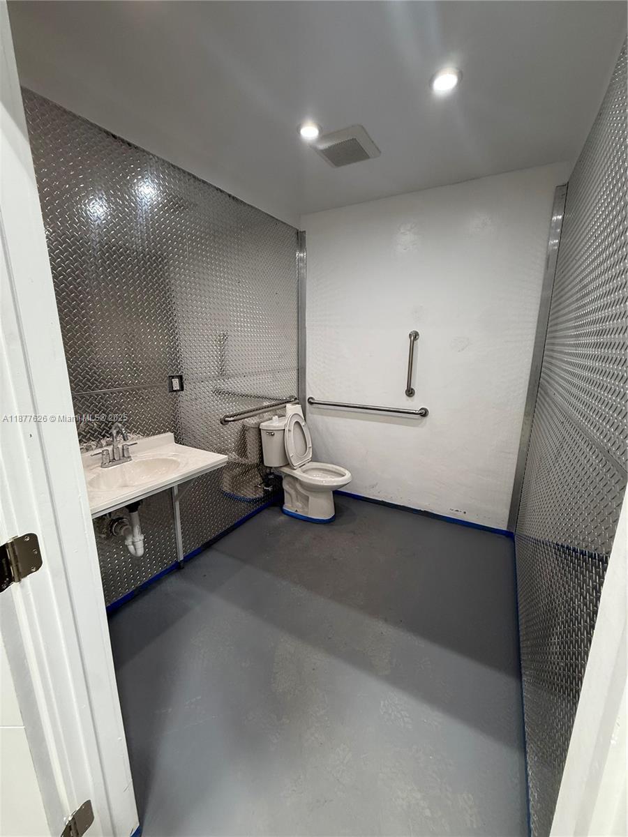 A commercial restroom features diamond plate metal walls, a sink, and a toilet with grab bars — 572 NW 72nd St, Miami FL 33150, MIAMI, FL