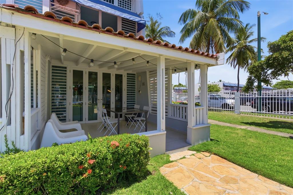 A covered patio with outdoor furniture sits beside a stone walkway and a green lawn — Villas de Playa II DORADO DEL MAR UNIT BB-2, DORADO, PR